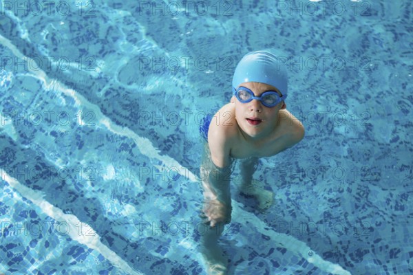 Little boy in swimming pool. Blue swimming pool