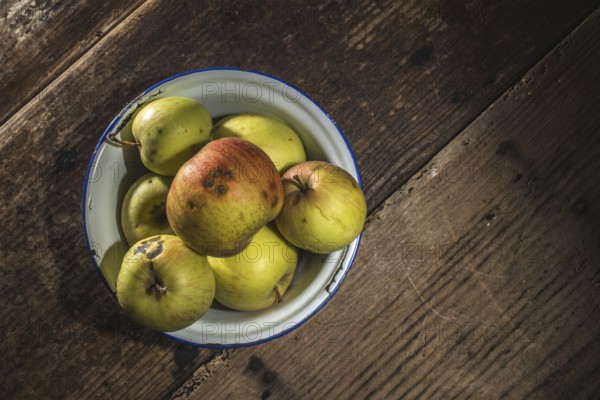 Apples in vintage metal cup on white wooden table