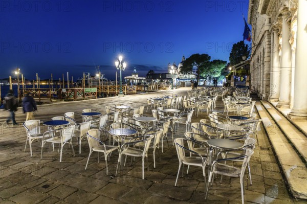 Restaurant tables on the promenade, evening mood at blue hour, Venice, Italy