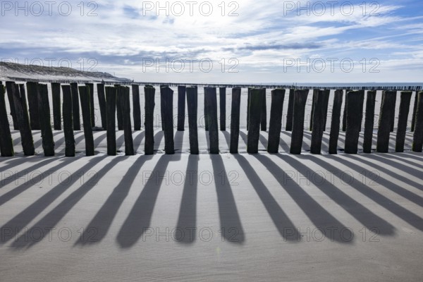 Old, weathered volleyball net on the beach in front of the dunes with sea and blue sky in the background, Groede, Zeeland, Netherlands