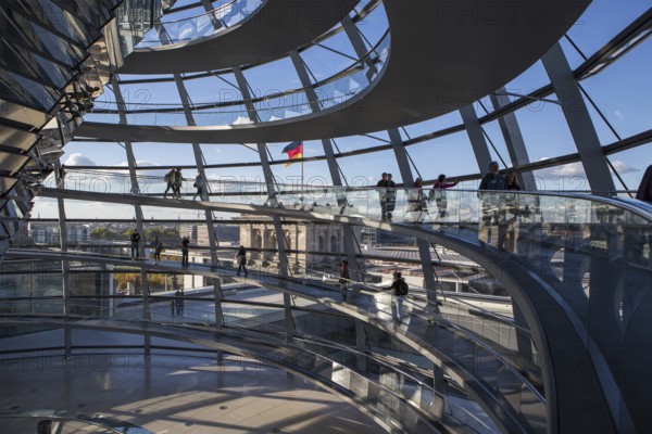 The shimmering Reichstag dome shines in all its splendour as visitors explore the modern interior. Glass and steel merge harmoniously and offer a breathtaking view of the bright blue sky and the flag waving proudly. An unforgettable experience in the heart of German democracy