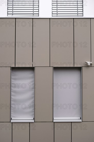 A modern office building façade with sheet metal cladding and an installed surveillance camera