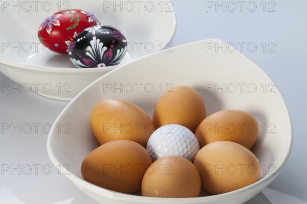 Two white ceramics bowls, easter eggs and golf balls