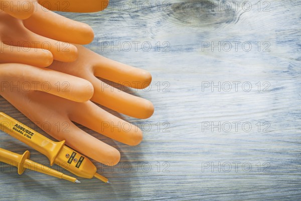 Electric tester pair of electricians gloves on wooden board electricity concept