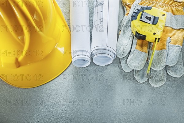 Set of blueprints building helmet safety gloves measuring tape on concrete background