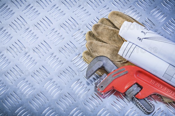 Pipe wrench engineering drawings leather safety gloves on fluted metal plate construction concept