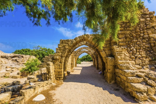 Sunny spring day. Arched passage - covered street. Picturesque ruins of the ancient seaport Caesarea. Israel. Concept of ecological and historical tourism