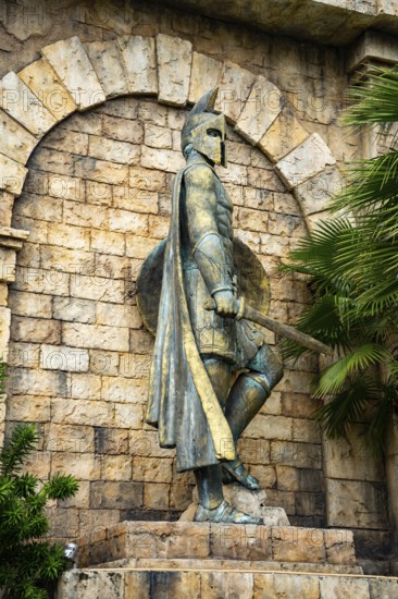 Close-up of an ancient statue with helmet and shield amidst stonework and greenery, palms, city, sun city, Phu Quoc, Vietnam