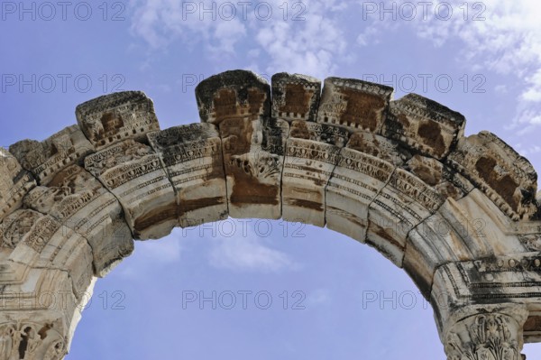 Ancient stone arch with decorative details against a blue sky, Turkey, Ephesus: Tourists encounter impressive evidence of Roman and Greek history on a round trip through western Turkey, Ephesus, Turkey