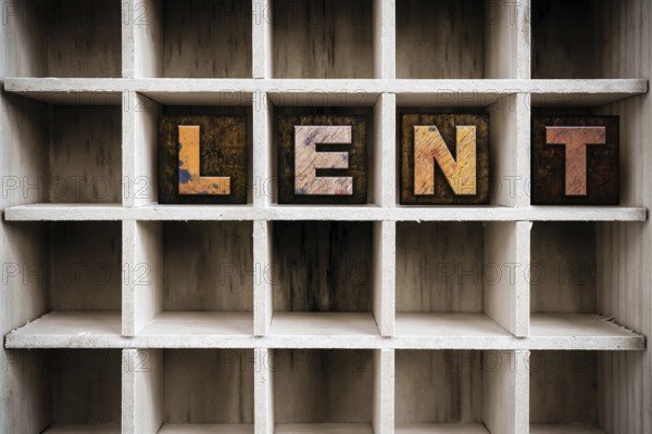 The word LENT written in vintage ink stained wooden letterpress type in a partitioned printer's drawer