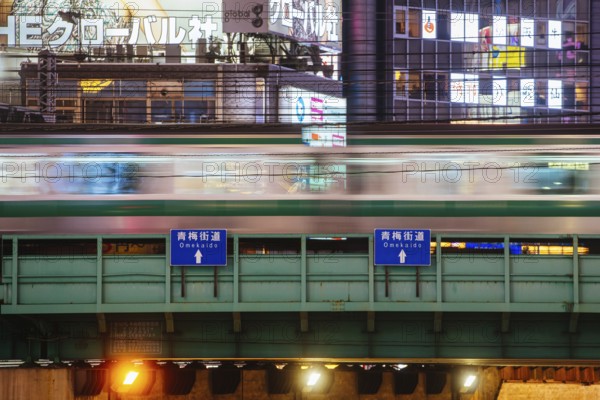 Shinjuku, Japan, 18 May 2019: Neon signs illuminate Tokyo?s busy Shinjuku neighborhood with bridge and trains at night