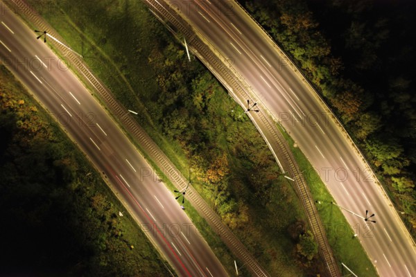 Top down view to road. Romantic night aerial photo of cars traveling. The light on the road at night in city. Background scenic road drone view. Tram railways background