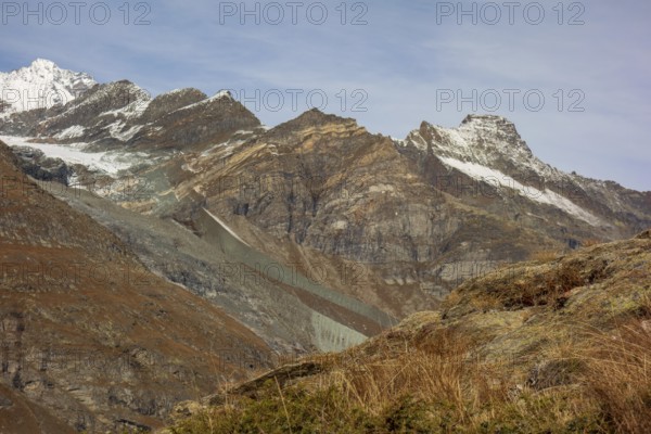 Barren mountain landscape with glaciers and snow-covered peaks under a blue sky, saas fee, switzerland