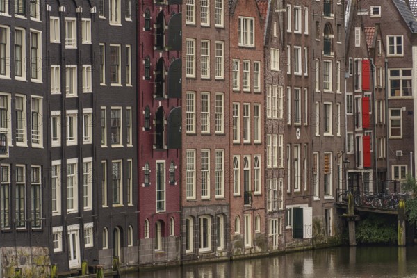 Dense row of townhouses along a canal with varied facades, Amsterdam, Netherlands