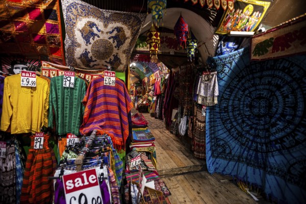 Colorful garments and textiles with sale signs in a vibrant market setting in the London Borough of Camden, Greater London, United Kingdom