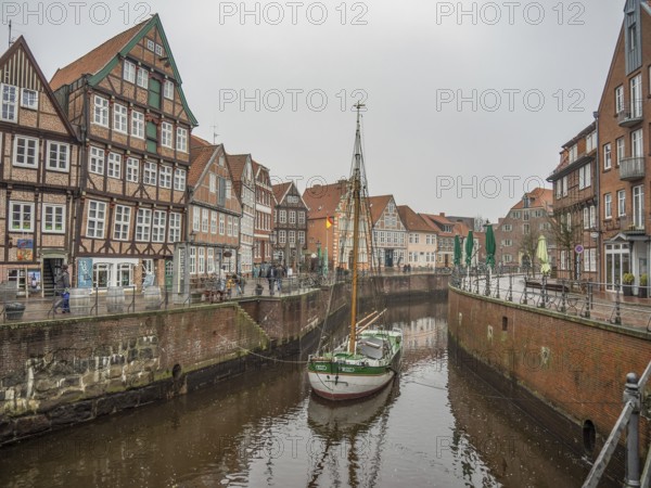 Foggy canal scene with half-timbered houses and a sailing boat, enhanced by the historical atmosphere, stade, germany