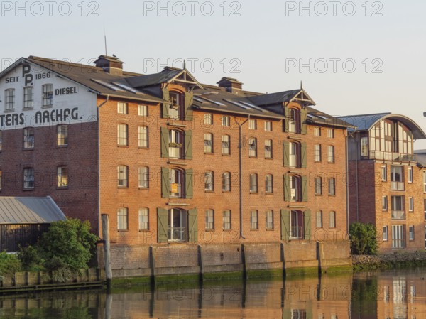 Historic brick building with several windows and reflection in the water at sunset, husum, schleswig-holstein, germany