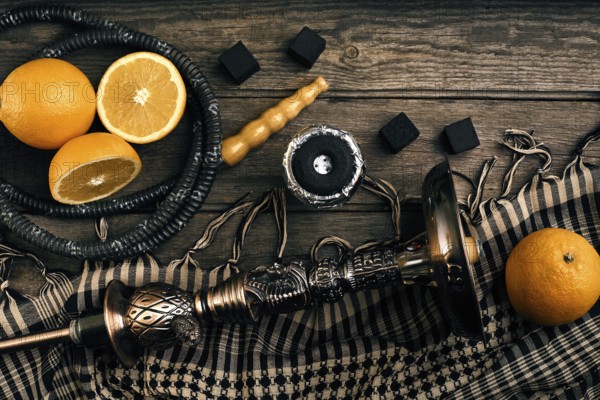 Dismantled parts of hookah on a wooden background with orange fruit. Top view. Flat lay. Copy space. Still life