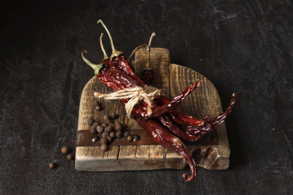 Dried chili peppers on a wooden board, dark photo