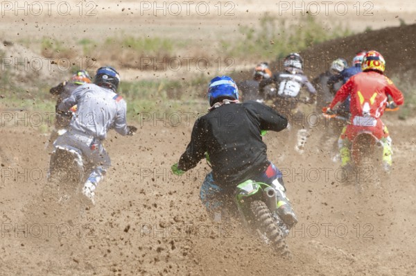 Unrecognized athletes riding a sports motorbike racing fast on a motocross track field. Challenge and competition