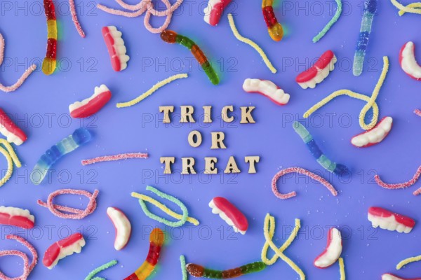 Halloween concept. Halloween party decorations with words TRICK OR TREAT, sweets, top view flat lay on blue background. Greeting card