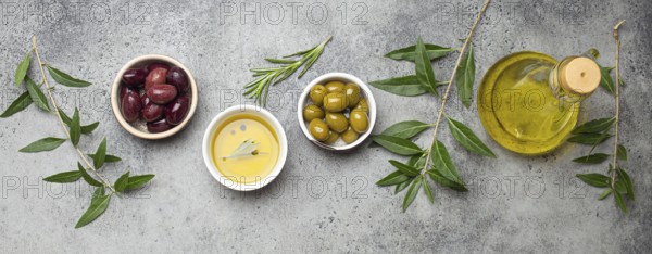 Composition with green and brown olives, extra virgin olive oil in glass bottle, olive tree branches on gray concrete stone rustic background overhead, Mediterranean concept, food photography, food photography