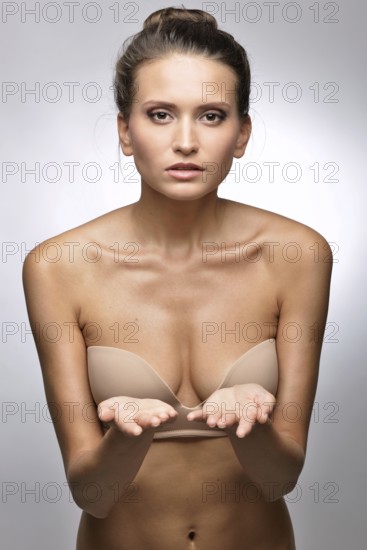 Beautiful woman in flesh color underwear showing by hand. Studio shooting