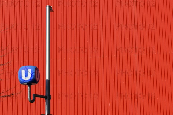 Underground symbol in front of a red, striped wall, urban traffic feeling, Vienna, Austria