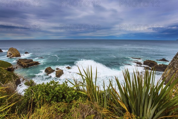 Foamy ocean surf before the storm. South Island, New Zealand. The picturesque coast of the Pacific Ocean near Cape Nugget. The concept of active, environmental and photo tourism
