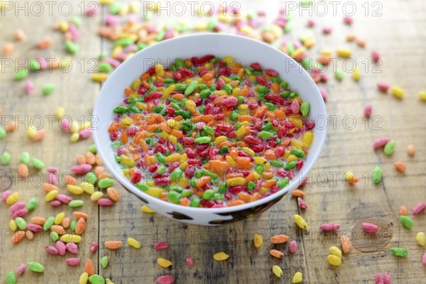Prepared breakfast with milk and colorful puffed rice in the bowl with spilled rice in the background