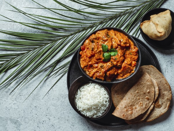 Indian cuisine dishes: tikka masala, rice, samosa, chapati, . Indian food on gray stone background with copy space. Assortment indian meal top view or flat lay
