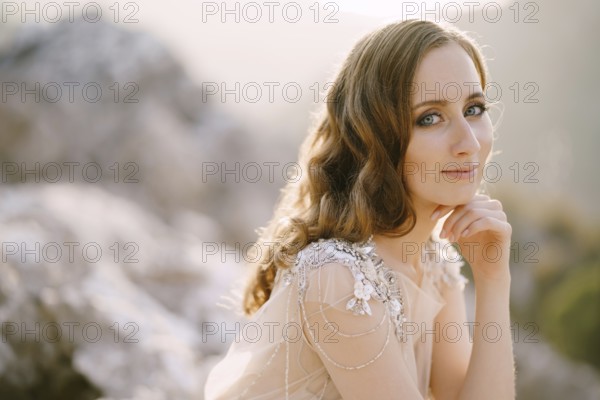 Smiling bride sits with her head propped up with her hand. Close-up.