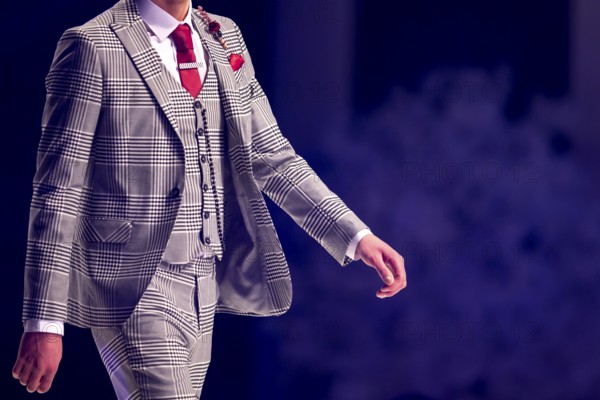 Male model walks the runway in grey suit during a Fashion Show. Fashion catwalk event showing new collection of clothes. Single model