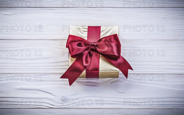 Golden gift-container with tied bow on wood board holidays concept
