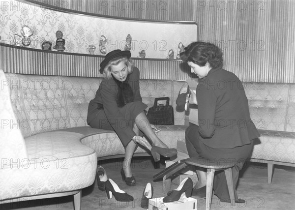 A young woman is well taken care of by a clerk in a shoe store. The dispatcher tries different shoes on the lady's feet. She has tried several different pairs of summer shoes and, judging by the picture, she has not yet found a pair that she thinks fits. Sweden 1948 Kristoffersson ref AO1-5