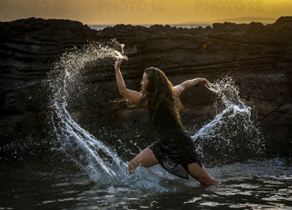 Middle-aged woman dancing and throwing water in the air, Maioris beach, llucmajor, Majorca, Balearic Islands, Spain