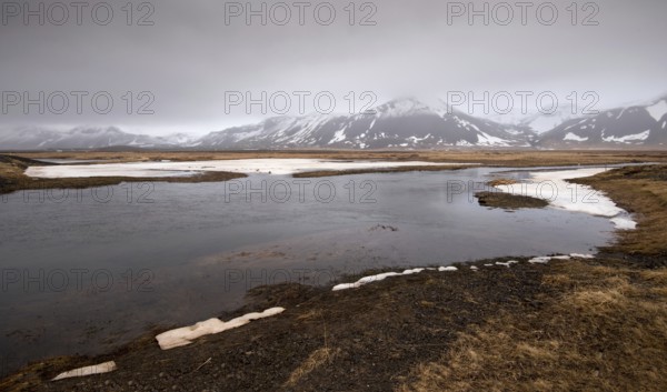 Typical Icelandic dramatic landscape with frozen lake and mountains covered in snow in Iceland