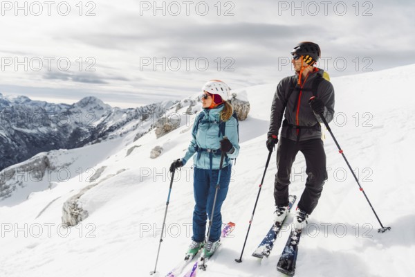Mountaineer backcountry ski touring in the mountains. Ski touring in high alpine landscape with snowy trees. Adventure winter extreme sport.