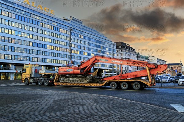 Mercedes-Benz Actros truck low loader trailer Ruoppaustyo transports Doosan DX 300 LC excavator in city at dusk. Helsinki, Finland. December 19, 2019