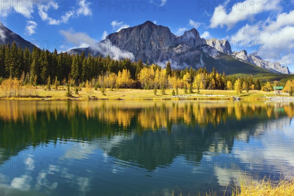 The Canadian Rockies. The city of Canmore in Banff Park. Bright autumn forest is reflected in the smooth water of the lake. The concept of active, ecological and photo tourism
