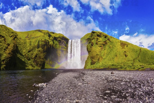 Iceland, waterfall Skogafoss summer, clouds of mist. Huge picturesque waterfall flowing from under a giant glacier