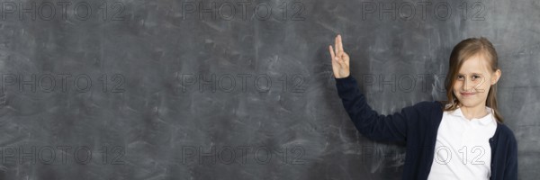 Schoolgirl shows on an empty school board. He is standing in the classroom at the chalkboard. Younger girl. Panoramic image