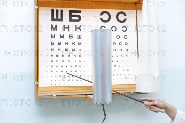 A Russian eye chart at an oculist and a hand with a pointer