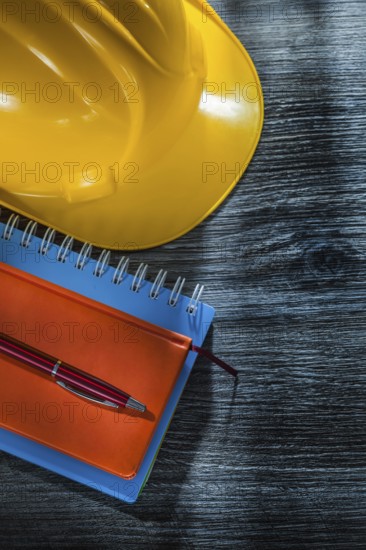 New notebooks pen safety building helmet on wooden board