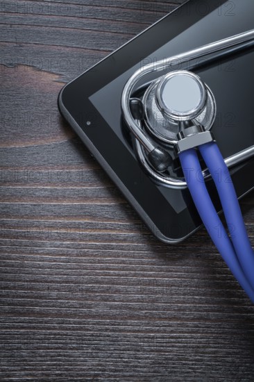 Medical stethoscope and touch-sensitive pad on vintage wooden background medicine concept