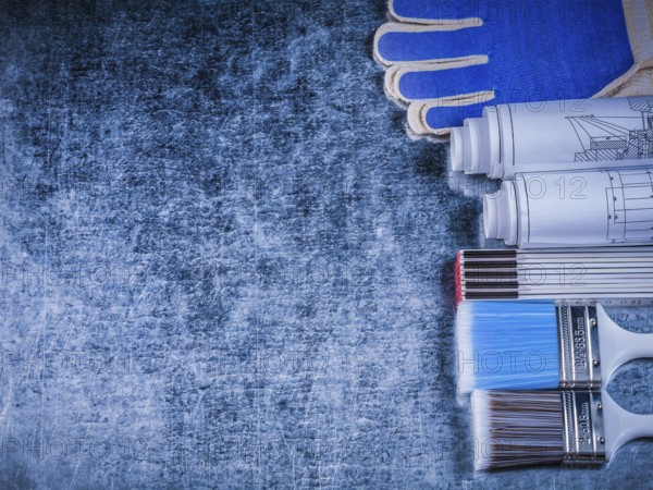 Copyspace of wooden meter paintbrushes protective gloves and rolled blueprints