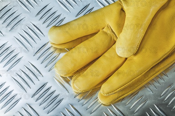 Pair of leather safety gloves on corrugated metal texture