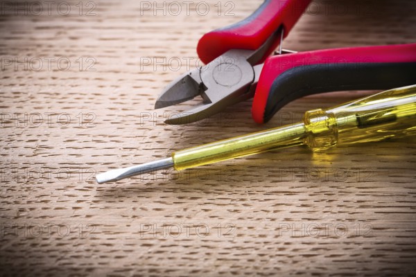 Very close up electrical tester and nippers on wooden board
