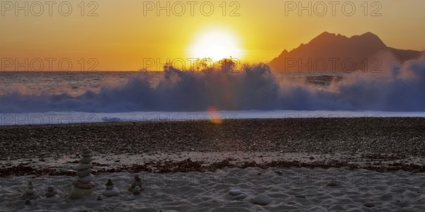 Land art in front of surf waves at sunset on Porto beach, Corsica