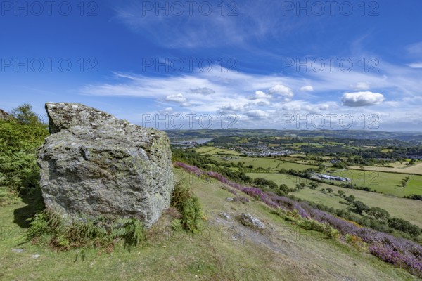 View from the mountains to Conwy Castle, medieval castle ruins surrounded by green fields and blue sky, with a rock in the foreground, Conwy, County Gwynedd, Wales, United Kingdom